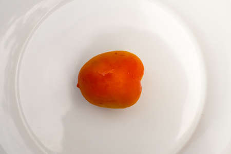One Orange Tomato on White Plateの写真素材