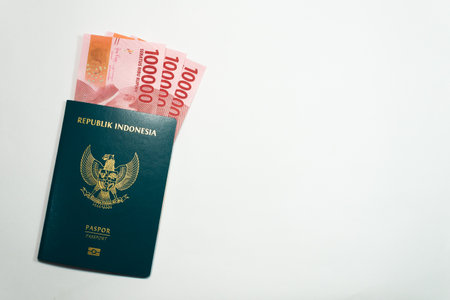 Indonesia passport and three 100000 rupiah currency money on white backgroundの写真素材