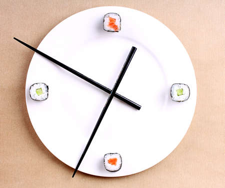 Sushi time in the form of a wall clock on a brown backgroundの写真素材