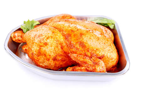 Uncooked whole marinated chicken in aluminum foil tray isolatedの写真素材