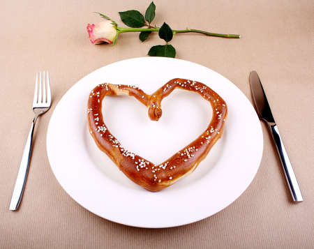 Fresh Pretzel in heart shape with cutlery and Rose