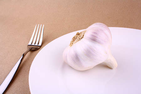 Healthy food - garlic on a white plate with fork, closeupの写真素材