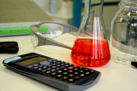 Red liquid in beaker on the table in the laboratory, soft focus
