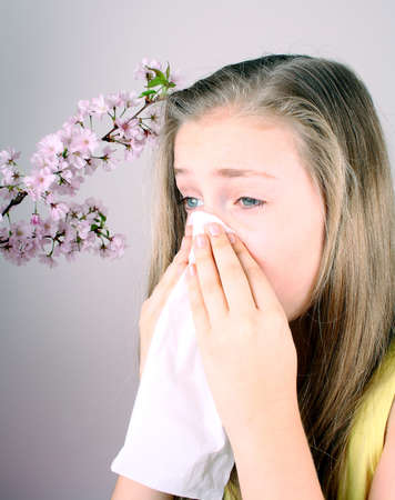 Girl blows her nose with handkerchief, cherry blossoms, health conceptの写真素材