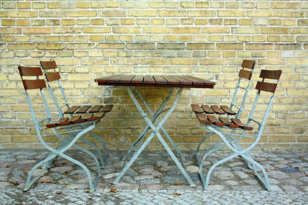 Four chairs and table in beer garden on brick wall, close upの写真素材