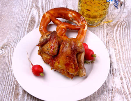 Chicken for Oktoberfest with pretzel, beer and radish, top view