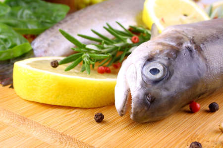 Two fresh rainbow trout with spices on bamboo board, extreme close upの写真素材