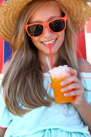 Beautiful girl in sunglasses and slush on beach, verticalの写真素材