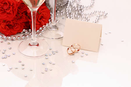 Two golden wedding rings with card, champagne glasses, red rosesの写真素材