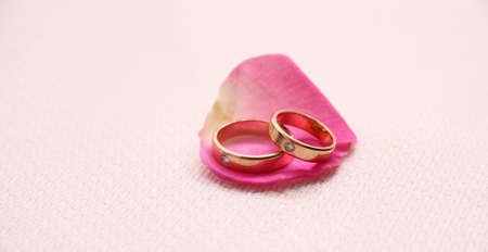 Set of wedding rings on pink rose petal, close upの写真素材