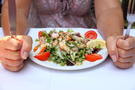 Mediterranean seafood salad and woman with knife and fork, concept of healthの写真素材