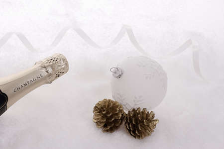 Champagne bottle in the snow with christmas tree ball, top viewの写真素材