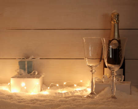 Gifts, Champagne glass and bottle on snow, in evening, fairy lightsの写真素材