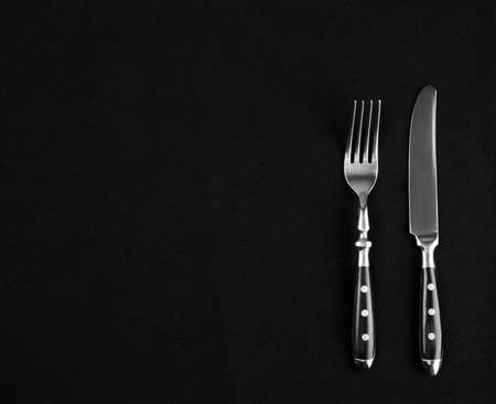 Fine cutlery on black placemat as menu board, top viewの写真素材