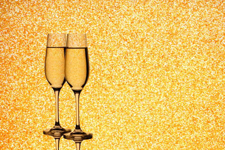 Two champagne glasses on blurred golden background, close upの写真素材