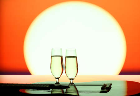 Two champagne glasses with guitar at sunset, close upの写真素材