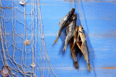 Dried rudd fish and fishing net on blue background, horizontalの写真素材