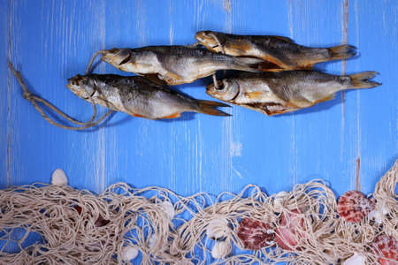 Dried rudd fish and fishing net on blue background, horizontalの写真素材