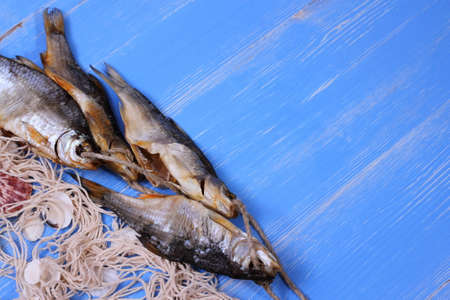 Dried rudd fish and fishing net on blue background, top viewの写真素材