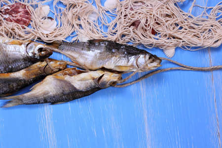 Dried rudd fish and fishing net on blue background, horizontalの写真素材