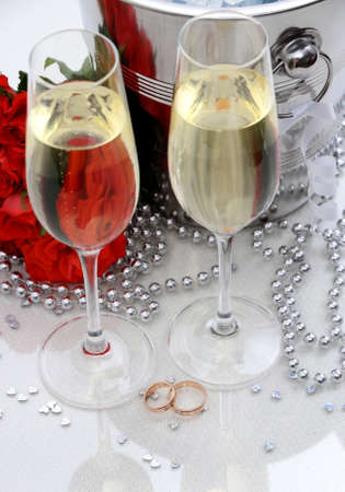 Two golden wedding rings, champagne glasses, red rosesの写真素材