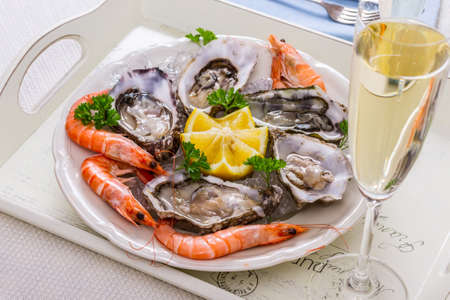 Champagne glass shell oysters with shrimp on serving tray top viewの写真素材
