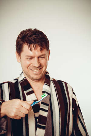 Laughing man in bathrobe brushing teeth in vintage lookの写真素材