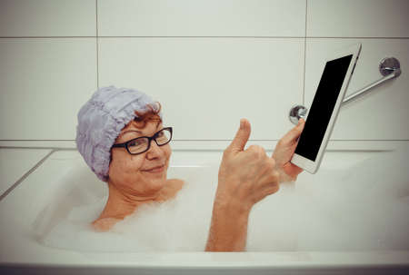 Woman in bathtub with tablet computers make ok, retro styleの写真素材
