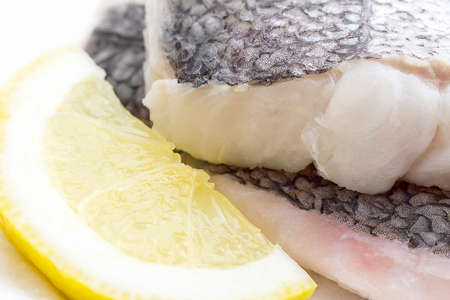 Hake fillet with skin and lemon, macro, as background, soft focus