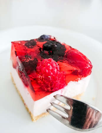 Cream cake with strawberries, raspberries, blueberries, coffee and forkの写真素材