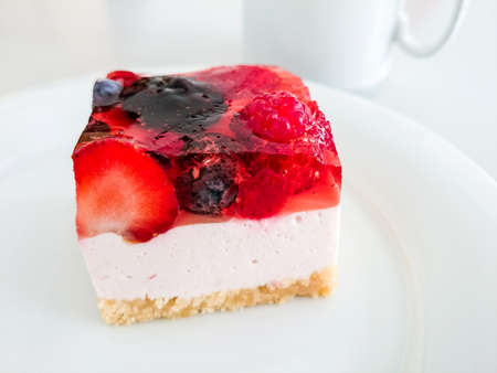 Cream cake with strawberries, raspberries, blueberries, coffee and forkの写真素材