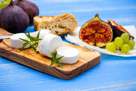 Feta cheese with ripe figs and grapes on blue, top viewの写真素材