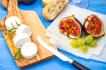 Goat cheese with ripe figs and wine on blue, top viewの写真素材