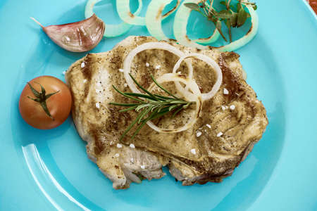 Juicy grilled pork chop with onion rings, stylish tintedの写真素材