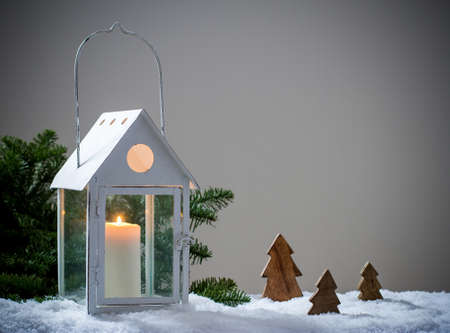 Lantern as house in snow with candle