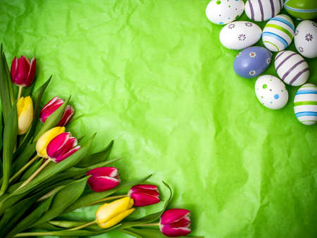 Eastern egg, tulips on green crumpled wrapping paper, top view