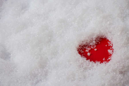 Single red heart in the snow, top viewの写真素材