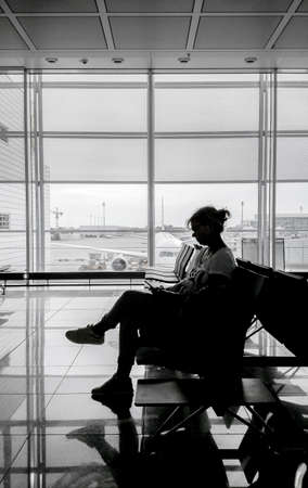 Silhouette of woman at airport waiting room, verticalの写真素材