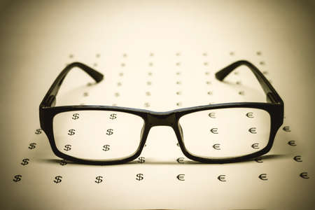 Glasses on paper with dollars and euros, soft focus