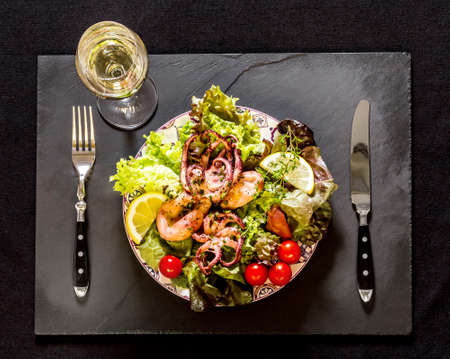 Octopus on blue plate with salad and lemon, on black slateの写真素材