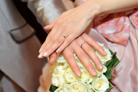 Wedding ring up an overlay of the hands of the bride and groom, you are shining in the background of brilliantly and bouquetの写真素材
