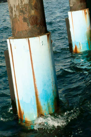 Steel column at the wharf washed at the wavesの写真素材
