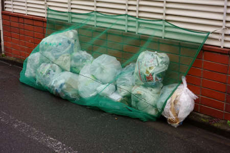 Household garbage discarded on the street covered with blue netの写真素材