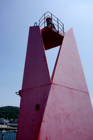 A lighthouse installed on the embankment of Hayama Marina under the scorching heat of midsummerの写真素材