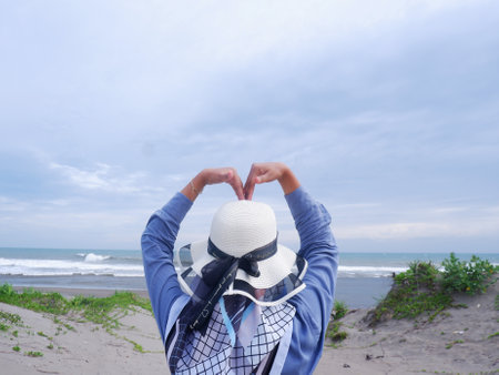 Woman wearing a white hat on the beach with blue sky background.の写真素材
