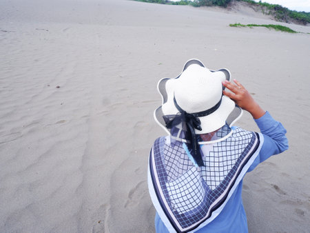 Woman in hat and blue shirt on the sand dunesの写真素材