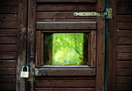 A wooden frame with lock blocking the view of nature and the window that signifies freedom  の写真素材