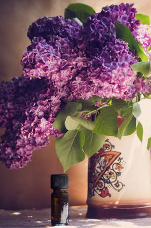 Oil from the fragrant flowers of lilac on the table. Verticalの写真素材