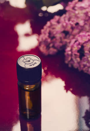 Oil from the fragrant flowers of lilac close up on the table. Verticalの写真素材