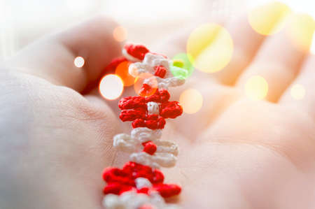 Braided red and white string bracelet on woman's hand.の写真素材